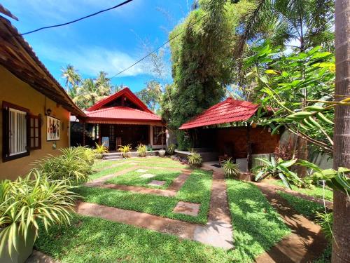 a garden outside a house with a red roof at Thara Cabana in Bentota