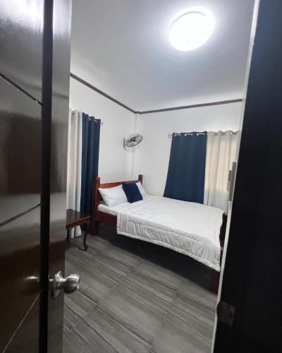 a small bedroom with a bed and a blue curtain at Charlotte's Vacation Home Busuanga Palawan in Buluang