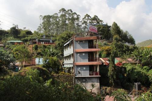 an apartment building on a hill with trees at Munnar Kaippalli Budget Homestay in Munnar