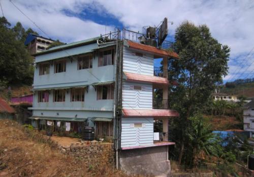 a building on the side of a hill at Munnar Kaippalli Budget Homestay in Munnar