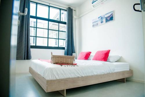 a bedroom with a bed with pink pillows and a window at บ้านคุณพระ แอท โกเตง in Surat Thani