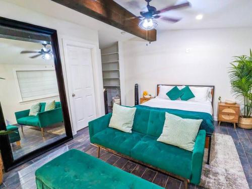a living room with a green couch and a bed at Casita Hosum: Modern WFH Garden Suite w/ Gazebo Outdoor Kitchen & BBQ in San Jose