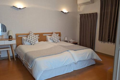 una camera da letto con letto con lenzuola bianche e scrivania di Roomy 4BR Home Sleeps 9／ShinOsaka／Large Groups ad Osaka