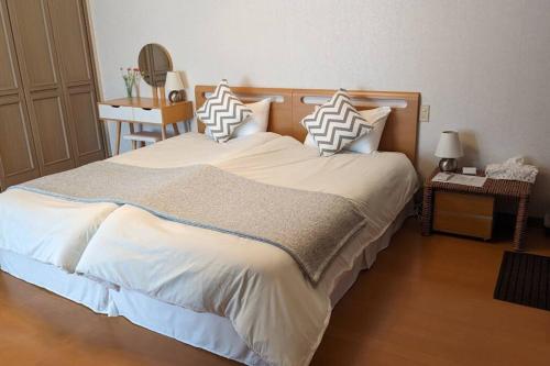a bedroom with a large bed with white sheets and pillows at Roomy 4BR Home Sleeps 9／ShinOsaka／Large Groups in Osaka