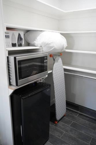 a microwave sitting on top of a stand in a room at Casita Hosum: Modern WFH Garden Suite w/ Gazebo Outdoor Kitchen & BBQ in San Jose