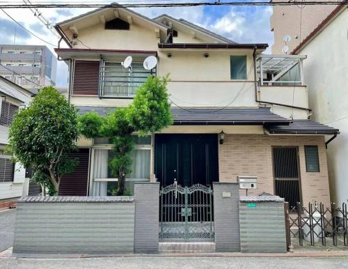 a house with a gate in front of it at Roomy 4BR Home Sleeps 9／ShinOsaka／Large Groups in Osaka