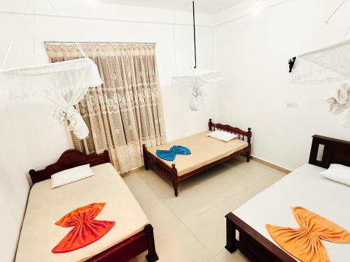 um quarto com duas camas e duas mesas em Golden Town Hostel em Tangalle