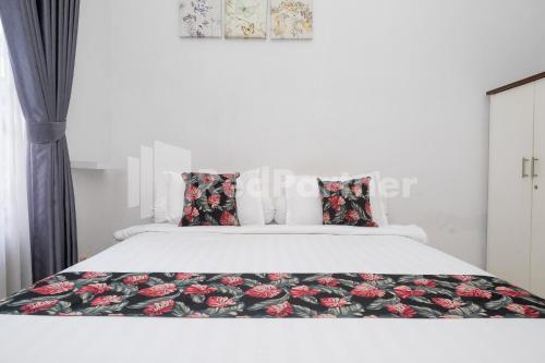 1 dormitorio con cama blanca y colcha de flores en Just 11 Boutique Syariah Mitra RedDoorz near UGM Yogyakarta, en Kejayan