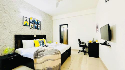 Schlafzimmer mit einem Bett, einem Schreibtisch und einem TV in der Unterkunft Olive Service Apartments - Vaishali Nagar in Jaipur