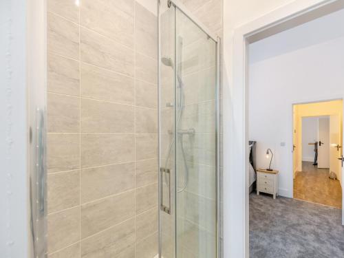 a shower with a glass door in a bathroom at Weavers Snug in Haworth