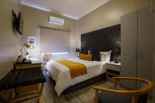 una camera d'albergo con un grande letto e una scrivania di Inani Hotel Gallagher a Midrand