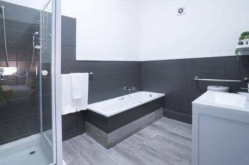 Inani Hotel Gallagher في ميدراند: حمام مع حوض استحمام ومغسلة