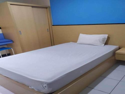 duże białe łóżko w pokoju z niebieskim ekranem w obiekcie OYO 93246 Kanditha Homestay w mieście Montongbuwoh