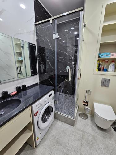 a bathroom with a shower and a washing machine at Magnificent apartment in NRG Oybek in Yakkasaray
