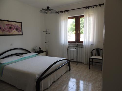 a bedroom with a bed and a window and a chair at Casa da Emanuela in Drežnik Grad