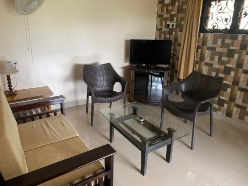 a living room with a couch and chairs and a tv at Casa Margarida in Calangute