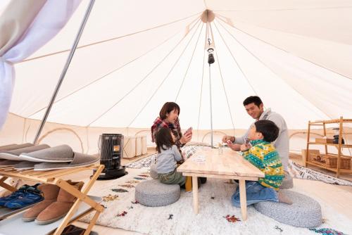 rodzina siedząca przy stole w namiocie w obiekcie 長崎鼻ビーチリゾート w mieście Kakaji