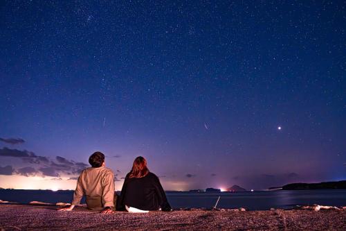 mężczyzna i kobieta siedzący na plaży w nocy w obiekcie 長崎鼻ビーチリゾート w mieście Kakaji