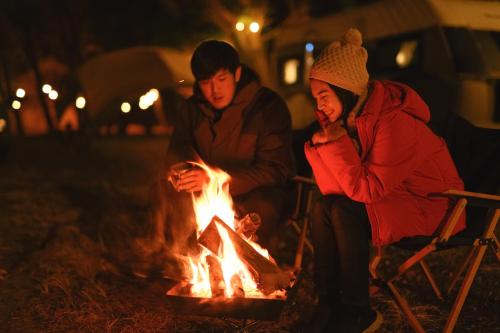 a couple of people sitting around a fire at 長崎鼻ビーチリゾート in Kakaji