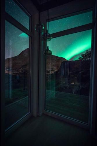 a room with a window looking at the northern lights at Gammelstua Seaview Lodge in Kongsjorda
