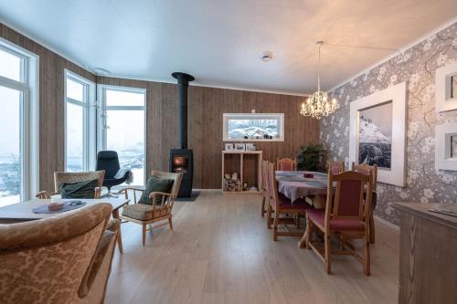un soggiorno con tavolo, sedie e camino di Gammelstua Seaview Lodge a Kongsjorda