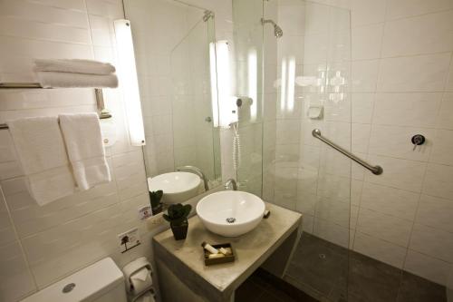 a white bathroom with a sink and a shower at Tierra Viva Cusco Saphi Hotel in Cusco