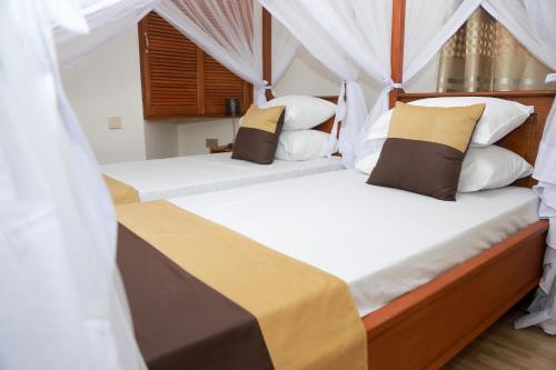 2 bedden in een kamer met witte lakens en kussens bij Wademac Arusha Inn Hotel in Arusha