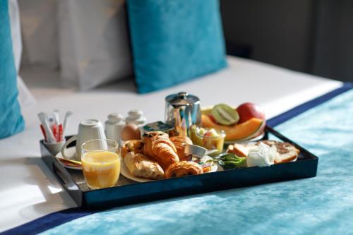 a tray of breakfast foods and orange juice on a bed at Prince Albert Montmartre in Paris