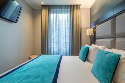 a bedroom with a large white bed with blue pillows at Prince Albert Montmartre in Paris