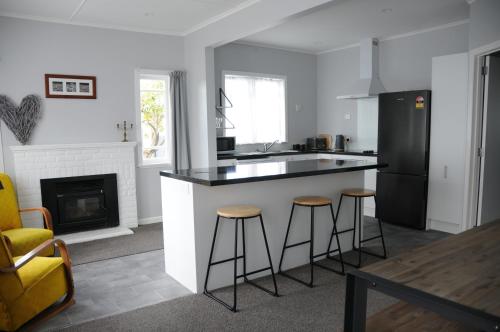 a kitchen with a black and white counter and stools at Nights on Broadway - THE HOUSE in Matamata