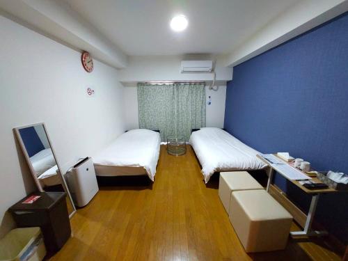 福岡市にあるComfort CUBE PHOENIX S KITATENJINのベッド2台、デスクが備わる小さな客室です。