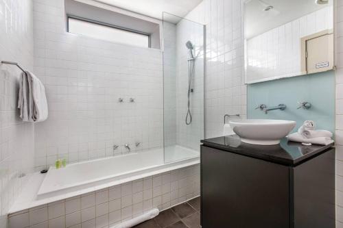 a bathroom with a tub and a sink and a bath tub at Collins Street Blues - Stay in the Heart of it All in Melbourne