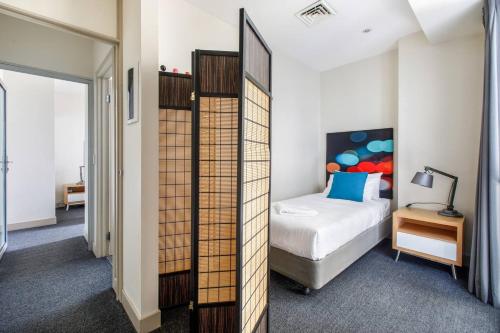 1 dormitorio con cama y espejo en Collins Street Blues - Stay in the Heart of it All en Melbourne