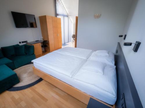 a bedroom with a large bed and a green couch at Weingut & Gästezimmer Zillinger in Ebenthal