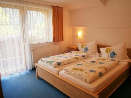 a bedroom with two beds and a large window at Alpenview Lechtal in Holzgau