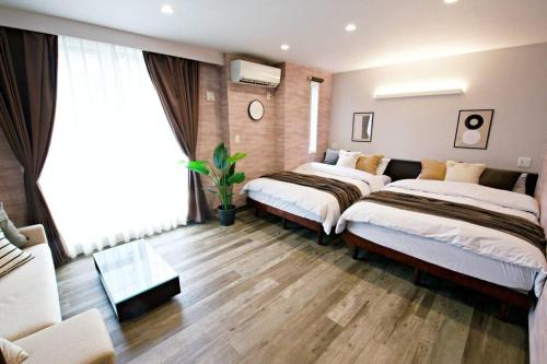 a bedroom with two beds and a couch at ザ・マスターズステイ世田谷経堂 201 in Tokyo