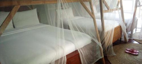 2 Betten in einem Zimmer mit weißen Moskitonetzen in der Unterkunft Lake Manyara View Luxury Tented Camp in Mto wa Mbu
