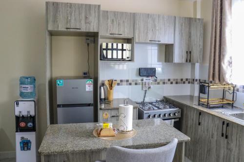 uma cozinha com armários de madeira e uma bancada em Alset Furnished Apartment-Suite F2 em Nakuru