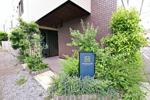 a sign in front of a building with plants at ザ・マスターズステイ世田谷経堂 201 in Tokyo