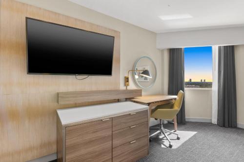 a hotel room with a desk and a television on a wall at Crowne Plaza Houston Med Ctr-Galleria Area by IHG in Houston