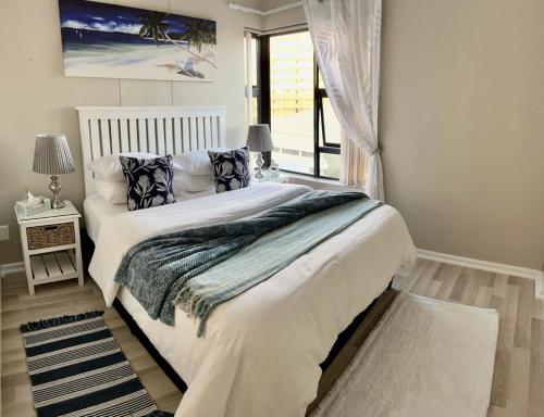 a bedroom with a large white bed with a window at Nautica 403 in Strand