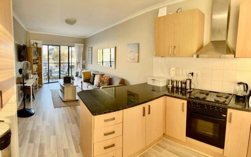 a kitchen with wooden cabinets and a living room at Beachside Bliss Strand in Strand