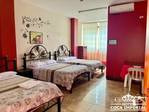 Habitación con 3 camas y pared roja. en Hotel Coca Imperial en Puerto Francisco de Orellana