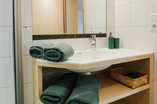 La salle de bains est pourvue d'un lavabo et de serviettes vertes. dans l'établissement Haus Margreth, à Mellau
