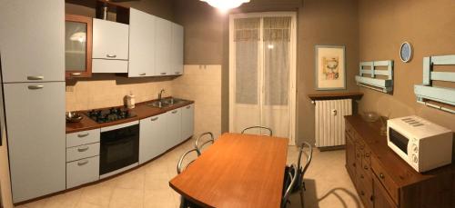 a kitchen with white cabinets and a wooden table at Appartamento Alfieri in Asti