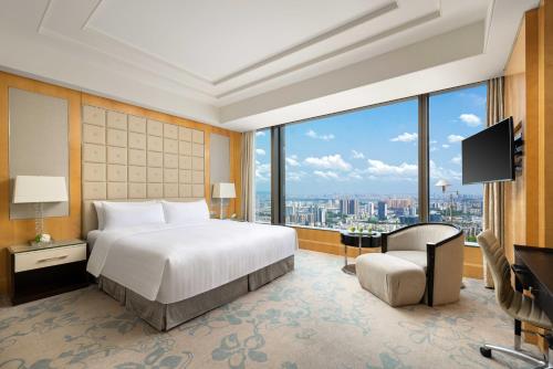 a bedroom with a bed and a desk and a television at Shangri-La Nanjing in Nanjing
