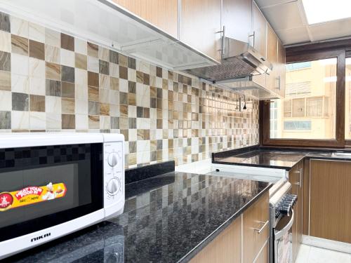 een keuken met een magnetron op een aanrecht bij Ras Star Residence - Home Stay in Dubai