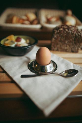 a egg on a plate with a spoon on a napkin at Stadthotel Kleiner Berg in Friedrichshafen
