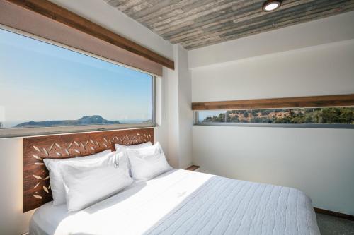 Schlafzimmer mit einem Bett und einem großen Fenster in der Unterkunft DOMUS AESTAS Luxury Residences in Plakias