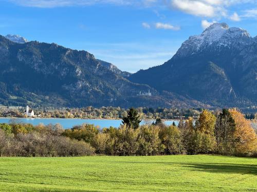 a field with a lake and mountains in the background at Haus Deutsch Berg-See- und Schloss Neuschwanstein Nähe in Roßhaupten